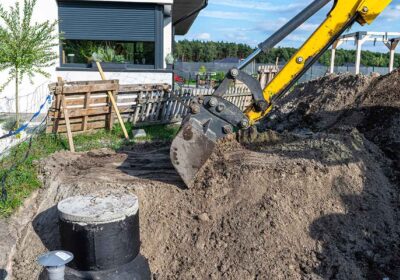 cadru cu un excavator care ajuta la amplasarea fosei septice langa o gospodarie